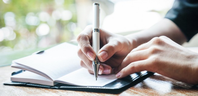 Close-Up of Hand Writing in Notebook