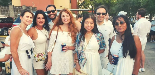 A group of people in white summer clothes posing for a picture