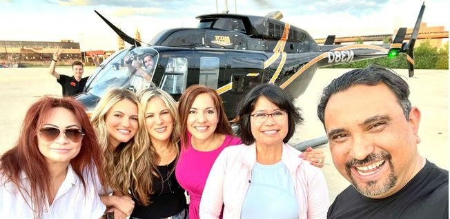 A group of people posing for a selfie in front of a helicopter