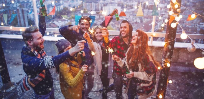 group of people with sparklers on rooftop terrace