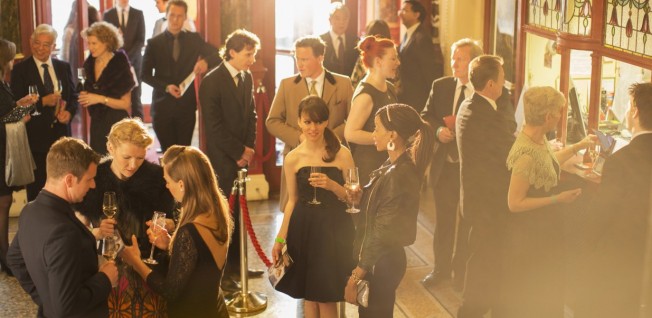 group of elegantly dressed people drinking champagne